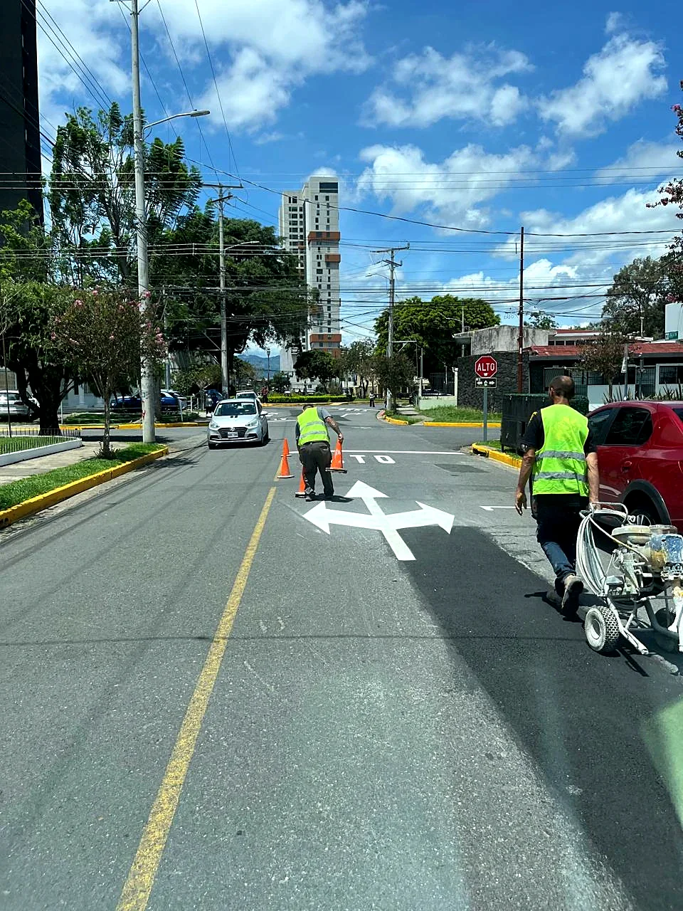 Personal con chaleco y conos pintando una flecha con equipo de demarcación en el sector de Escalante
