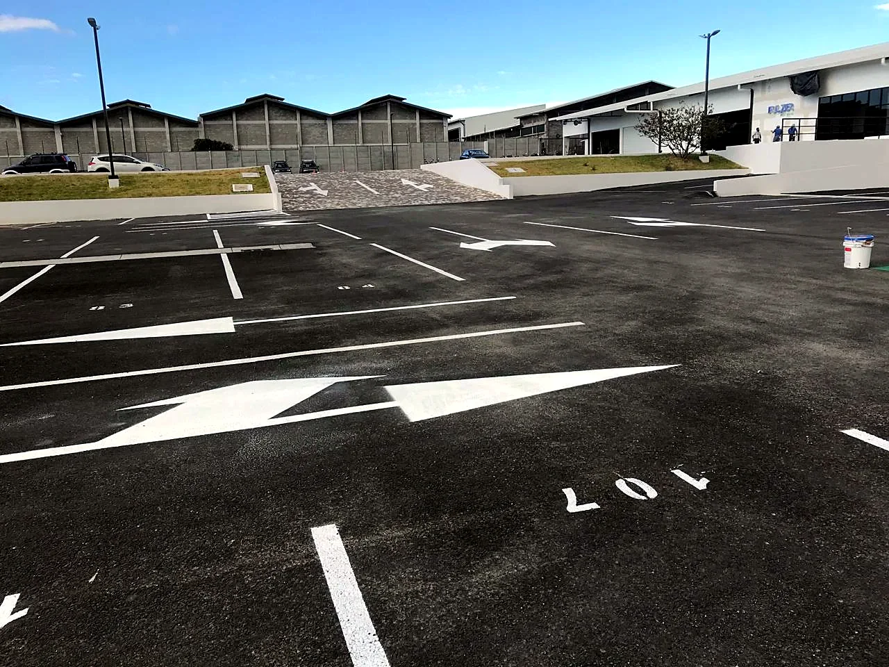 Flechas de circulación recién pintadas sobre asfalto nuevo en el parqueo de Fulzer Post Venta