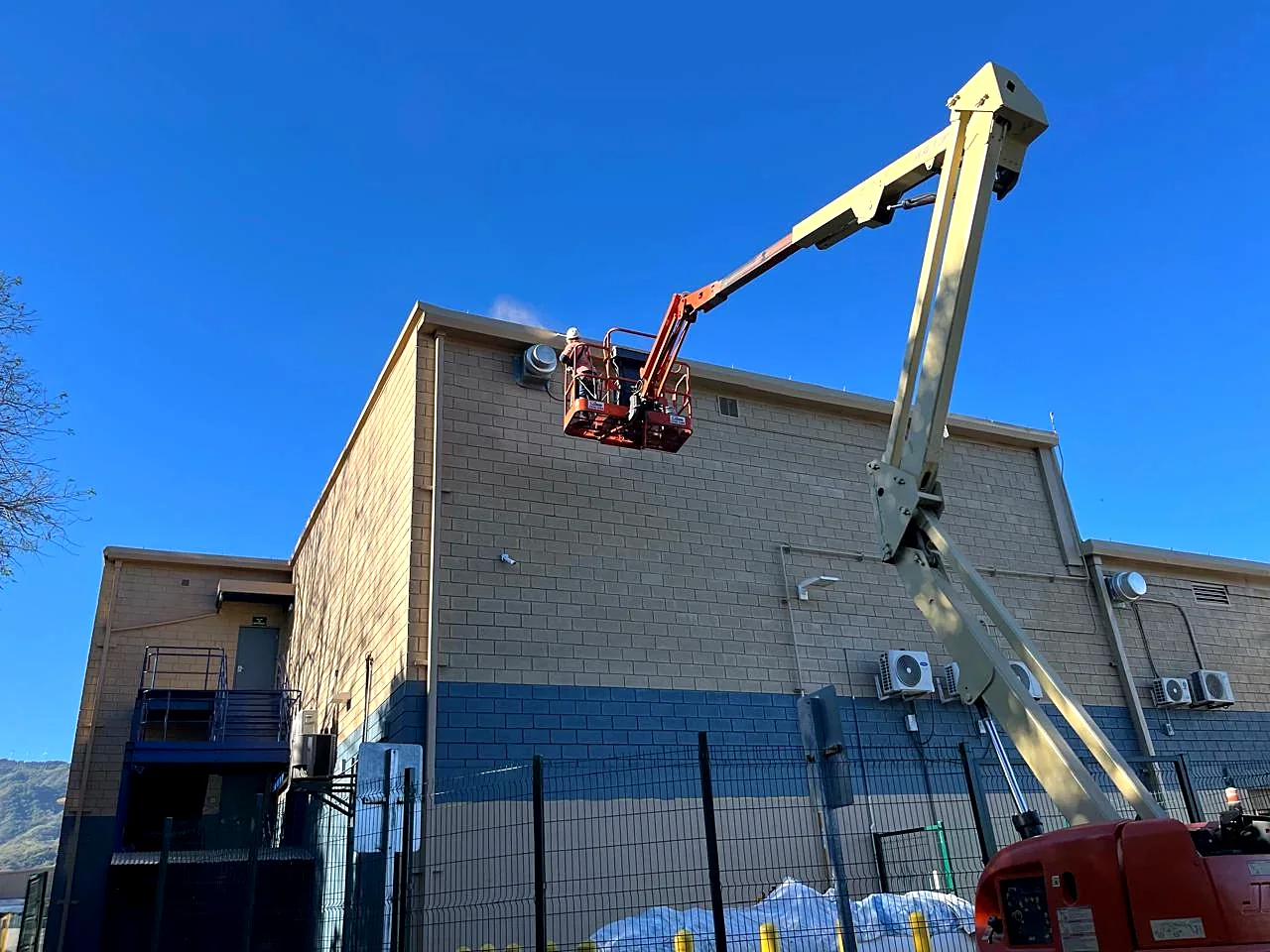 Aplicación a pistola en la parte alta del muro desde plataforma articulada, PriceSmart Santa Ana