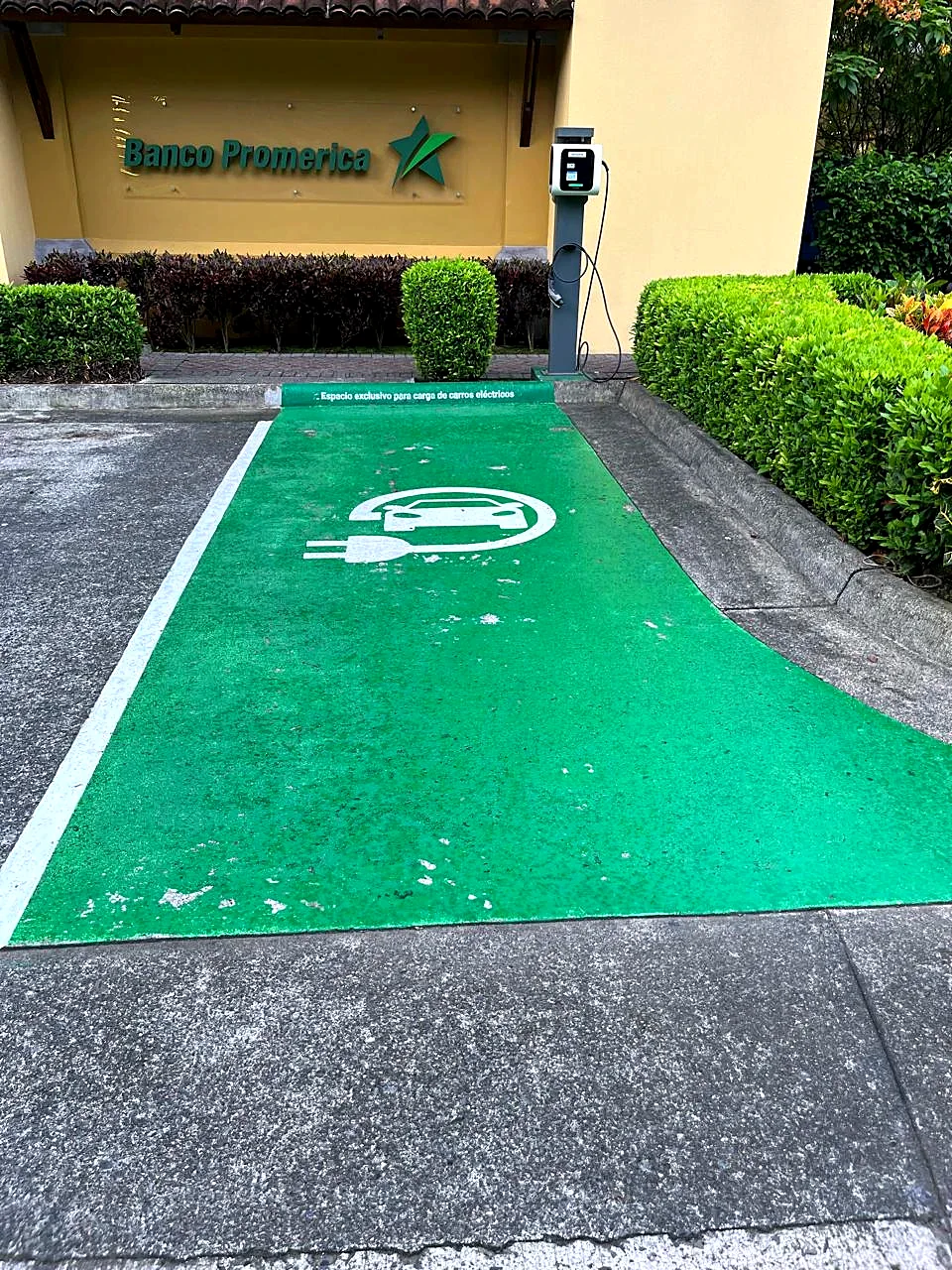Antes: espacio de carga eléctrica con pintura verde desgastada y desprendida, Banco Promerica