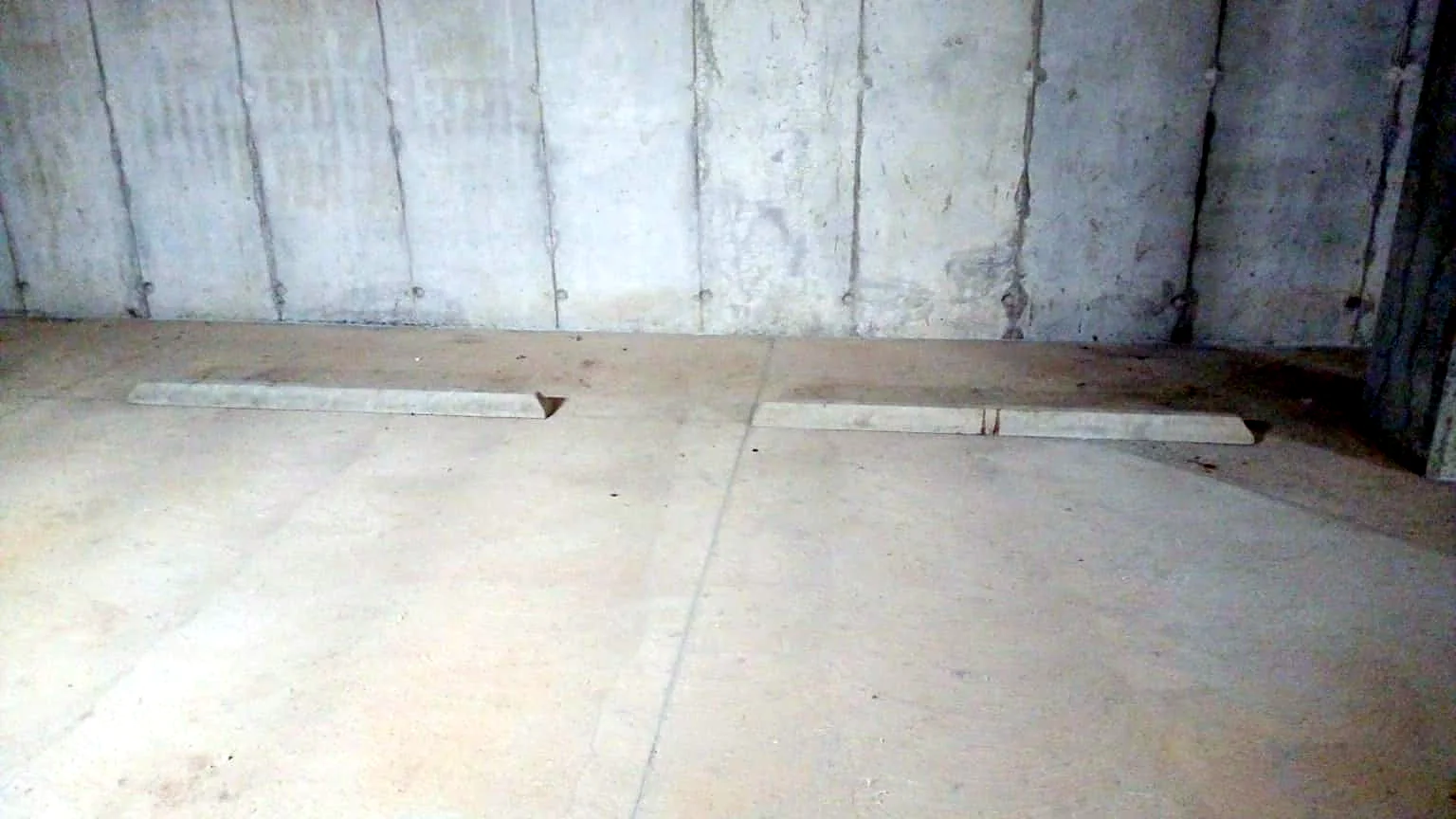 Antes: topes de concreto sin pintar contra la pared del sótano