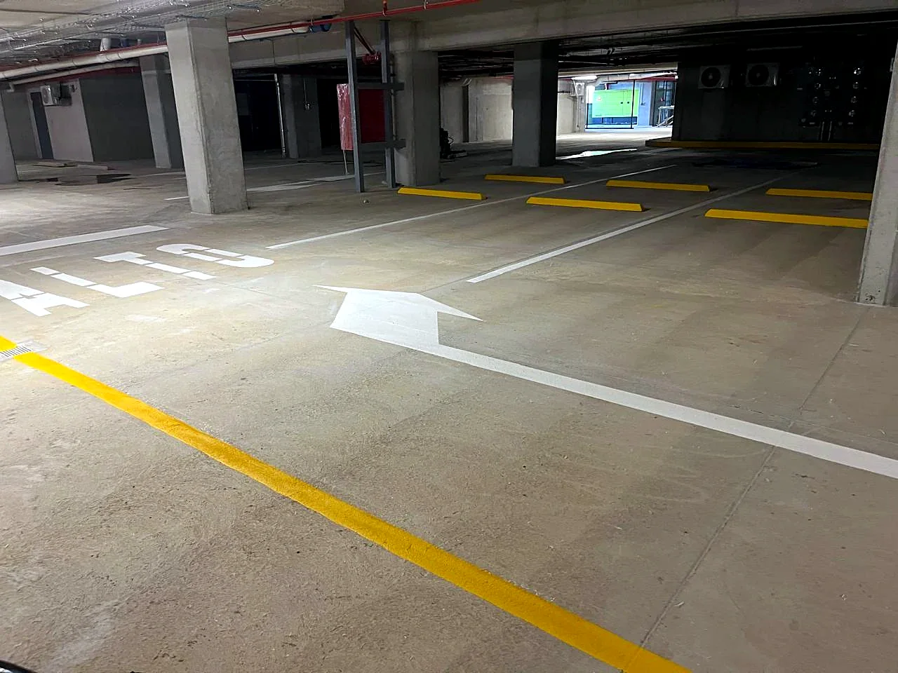 Sótano del Edificio SAVIA con flecha de circulación, ALTO y topes de parqueo pintados