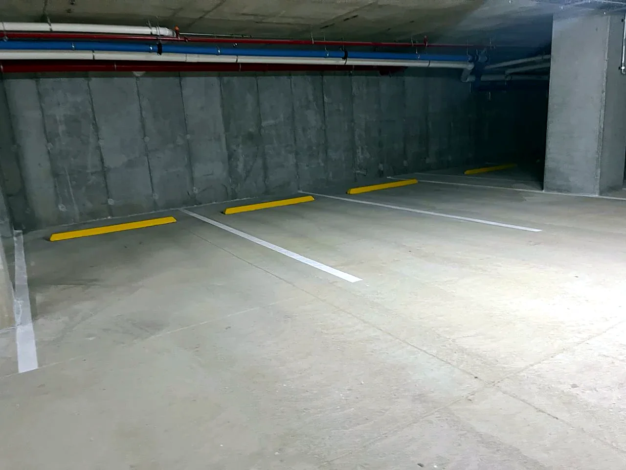 Después: espacios demarcados en blanco con topes amarillos a lo largo de la pared
